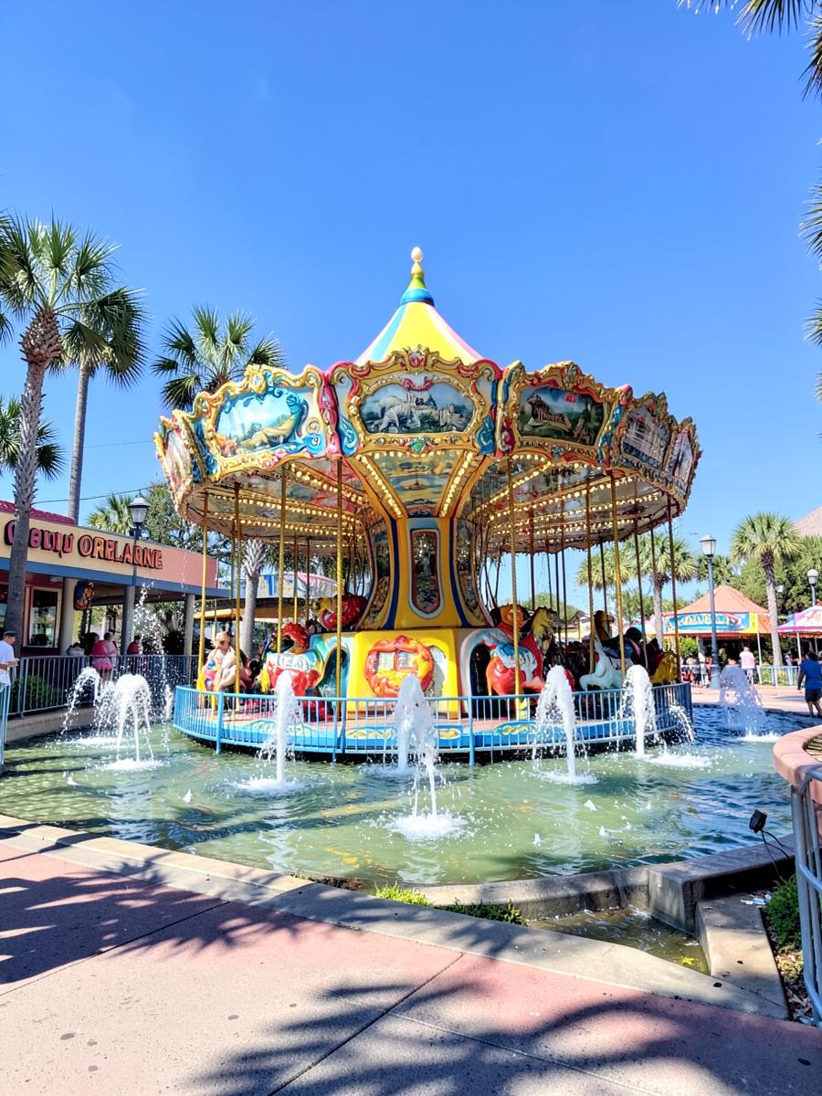 Bright Orlando theme park plaza with a colorful carousel and fountains